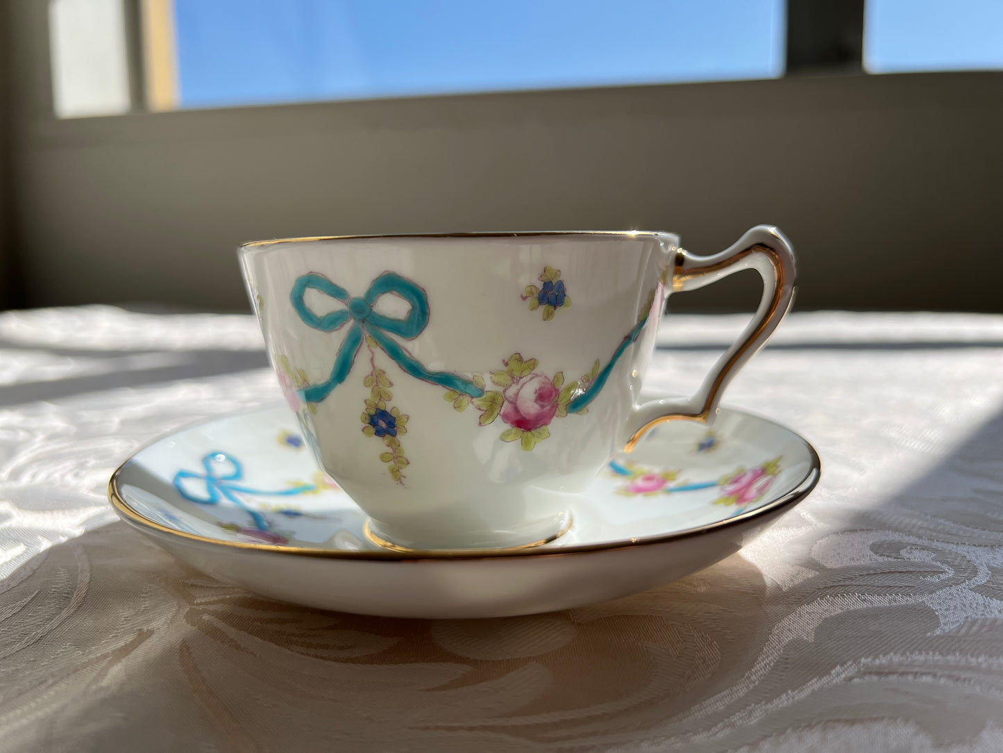 Crown Staffordshire bright blue enameled ribbon and looped bows pattern teacup and saucer